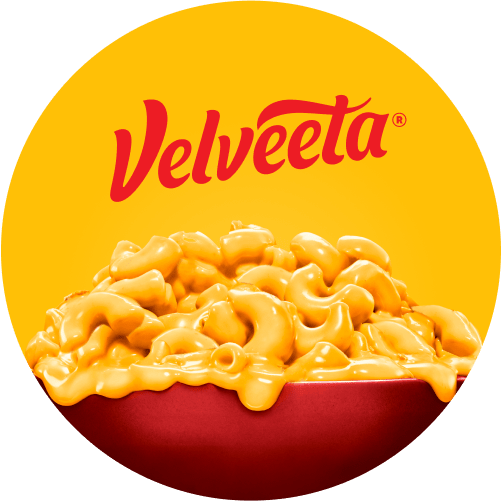 A creamy pasta bowl on a yellow background with the Velveeta logo above