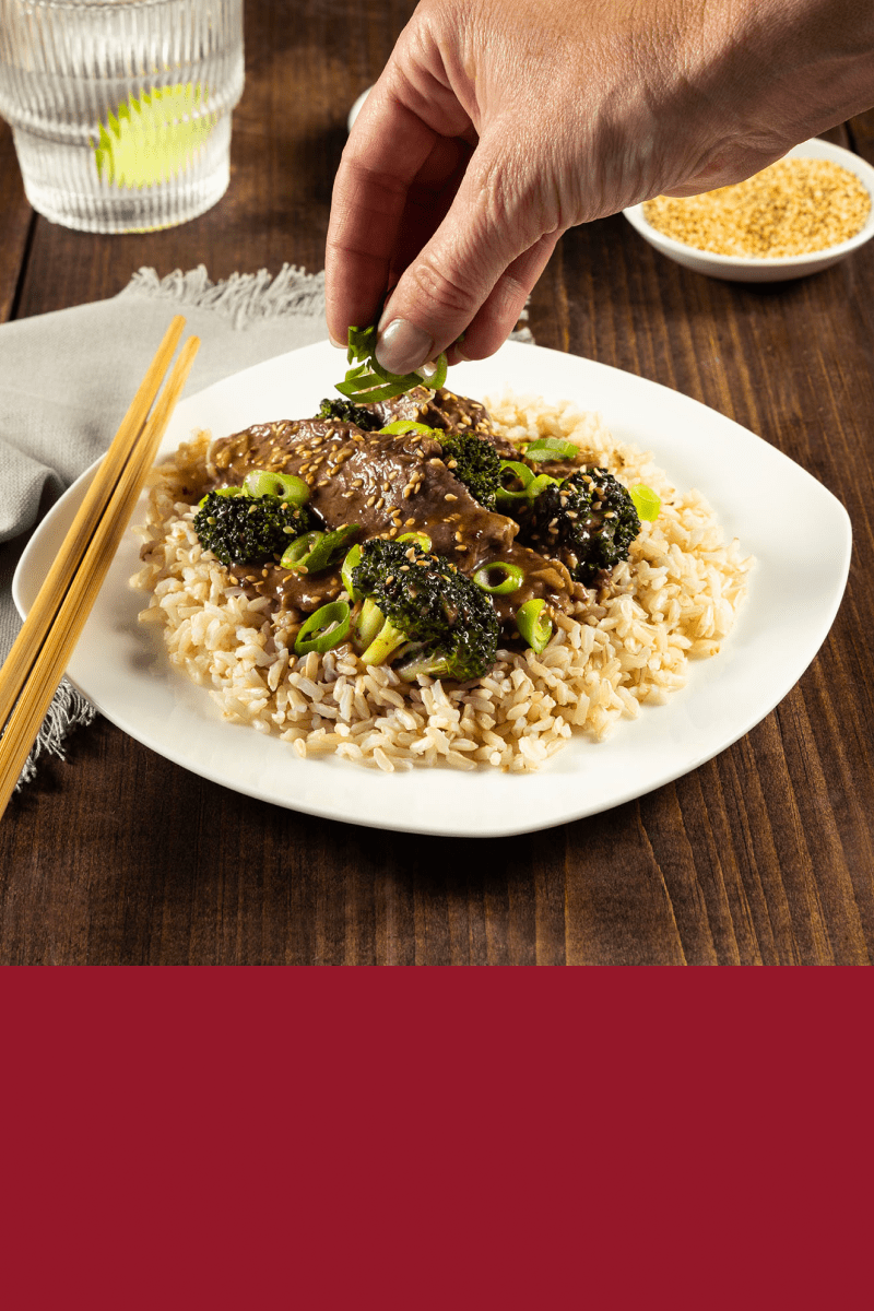 A plate filled with rice and Sesame Beef and Broccoli made with HEINZ HomeStyle Brown Gravy.