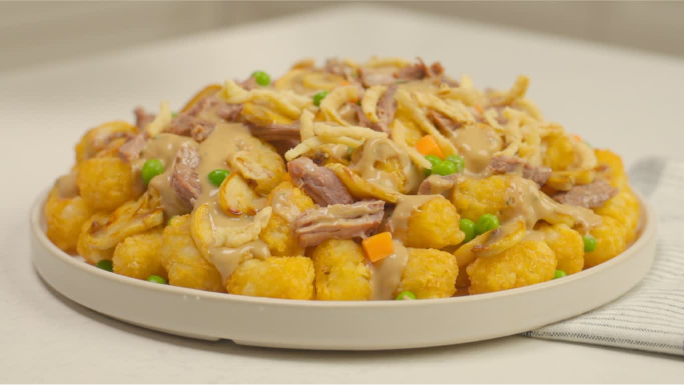 Pot roast and TATER TOTS loaded with veggies, mushrooms, onions and gravy on a plate ready to serve.