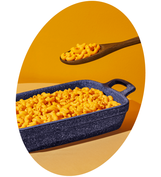 Close up of a large blue casserole dish of freshly baked Kraft Mac & Cheese with a wooden serving spoon ready to dish it up!