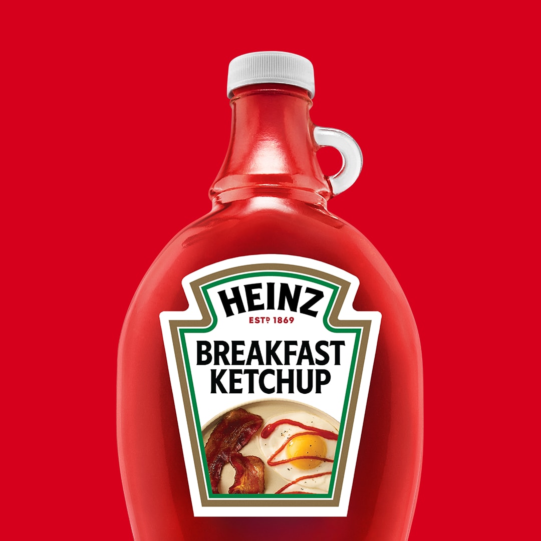 A bottle of Heinz Breakfast Ketchup against a red background.