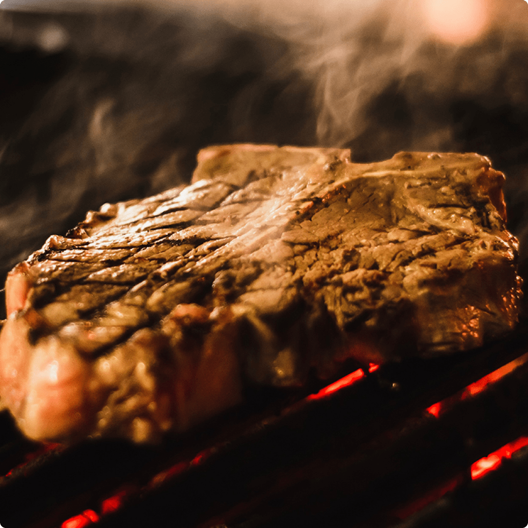 A t-bone steak on a red hot grill.
