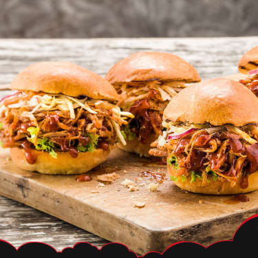 Four pulled pork sandwiches sitting on a platter.