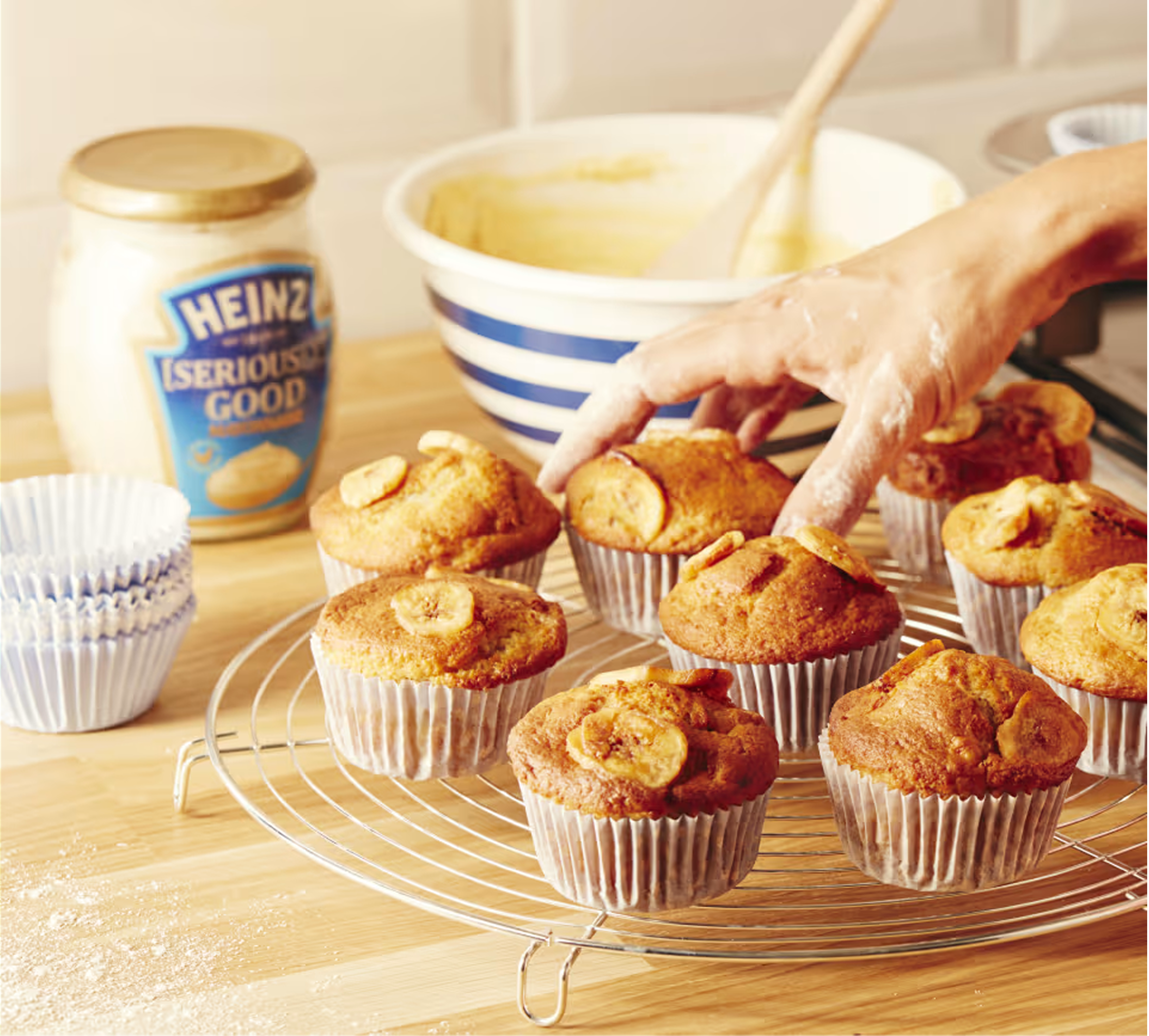 En närbild av nybakade bananmuffins som svalnar på ett metallgaller. Muffinsen är gyllenbruna och toppade med skivor av banan