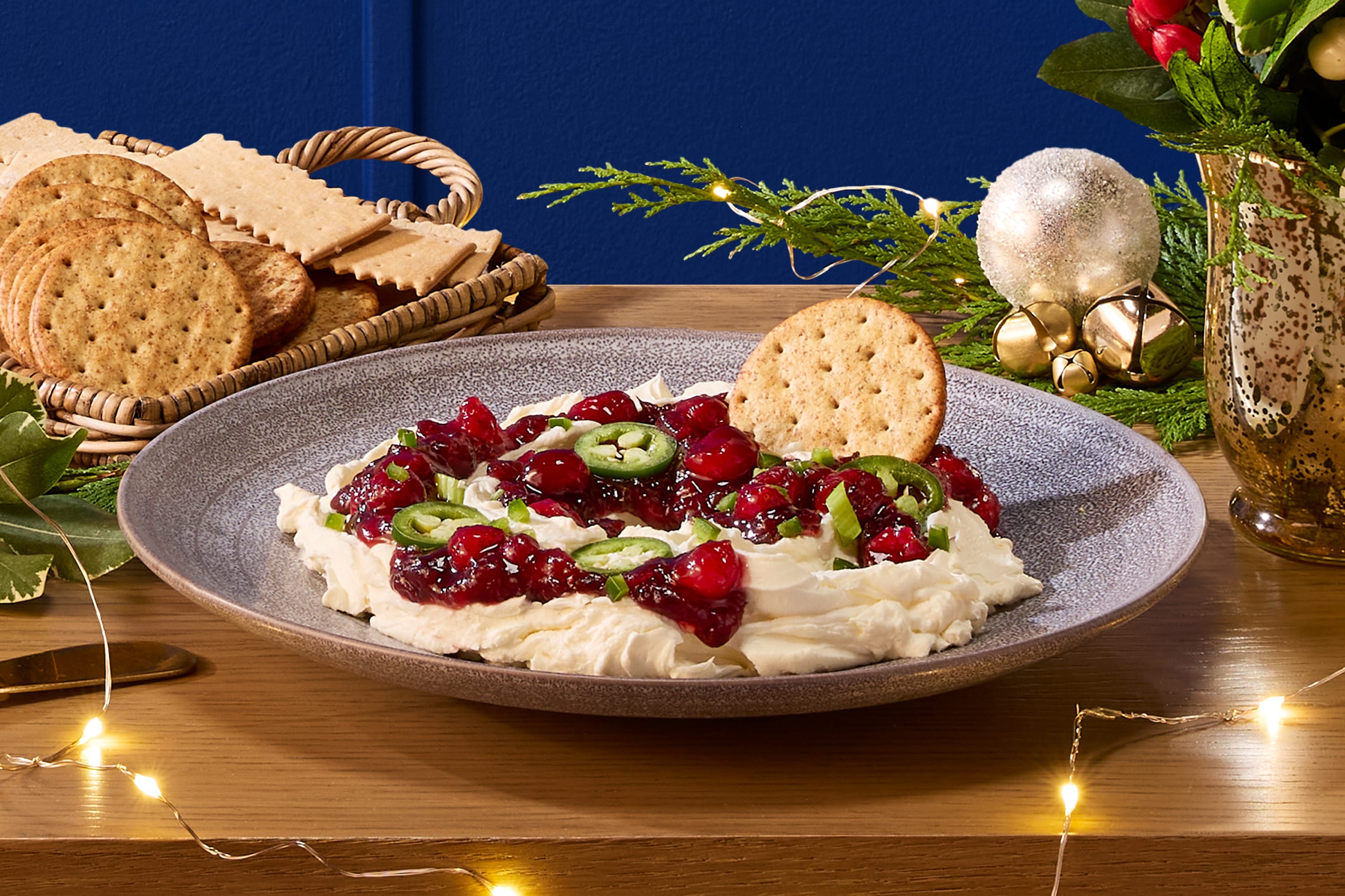 A festive Philadelphia cream cheese dip, topped with vibrant cranberry sauce, fresh jalapeño slices, and green onions.