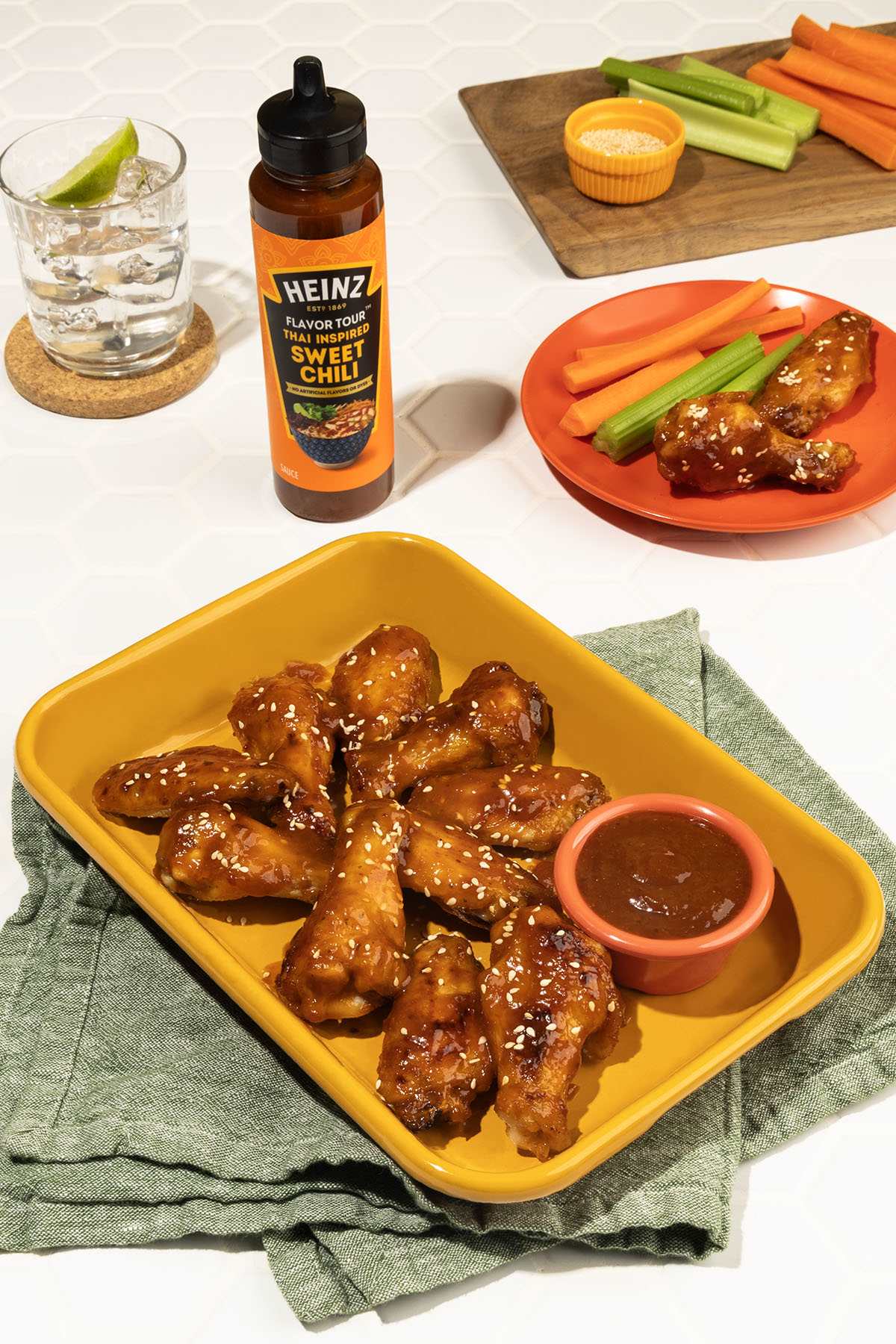 A close-up overhead shot of a rectangular, mustard-yellow dish filled with glistening air-fried chicken wings coated in Heinz