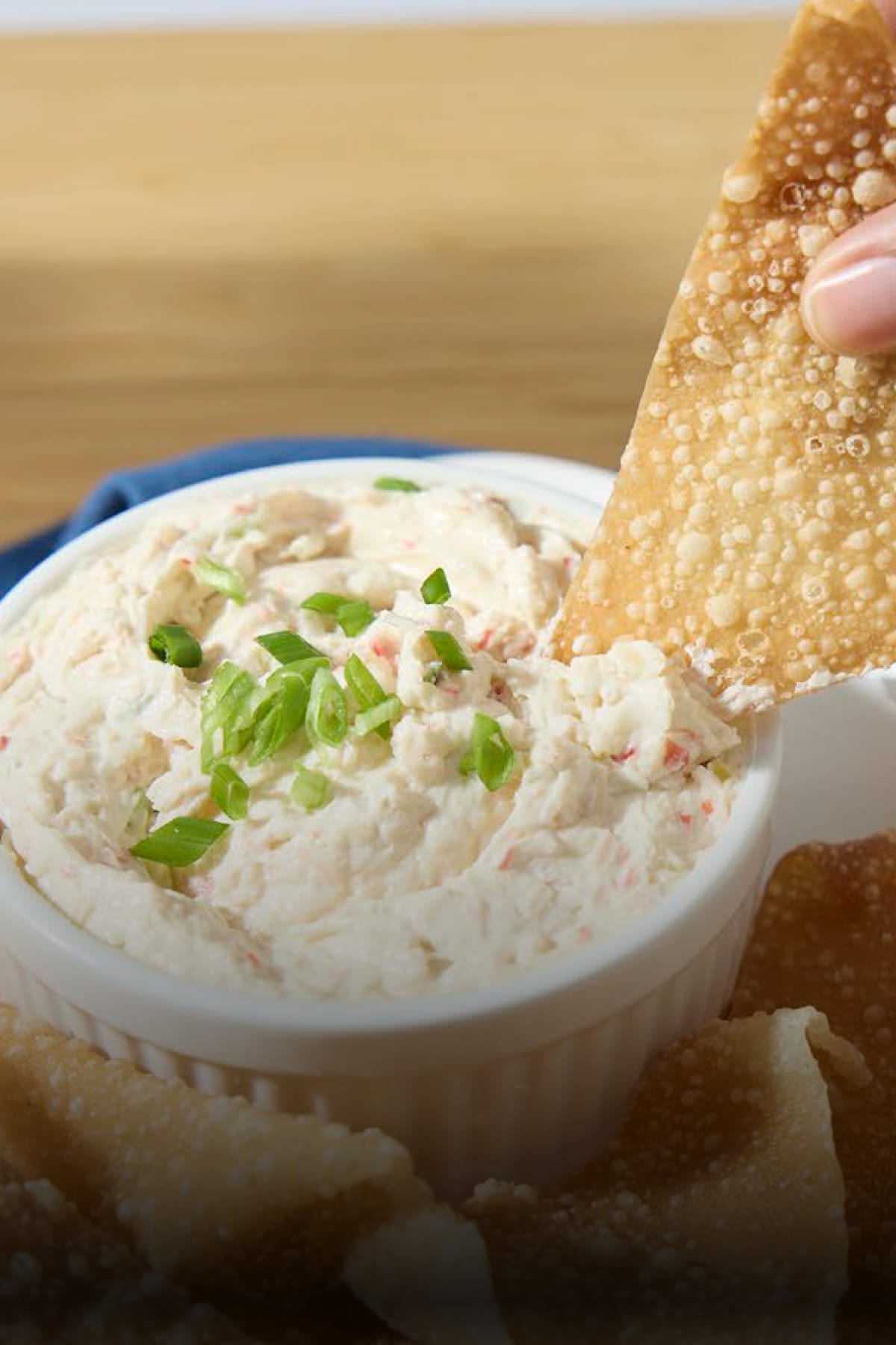 Creamy hot crab dip made with PHILADELPHIA Cream Cheese, served in a white bowl with crispy fried wonton chips.
