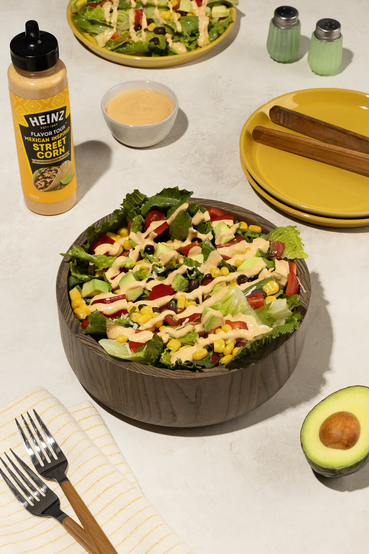 A vibrant and colorful image featuring a dark wooden bowl filled with a Southwest Salad. The salad consists of lettuce, corn,