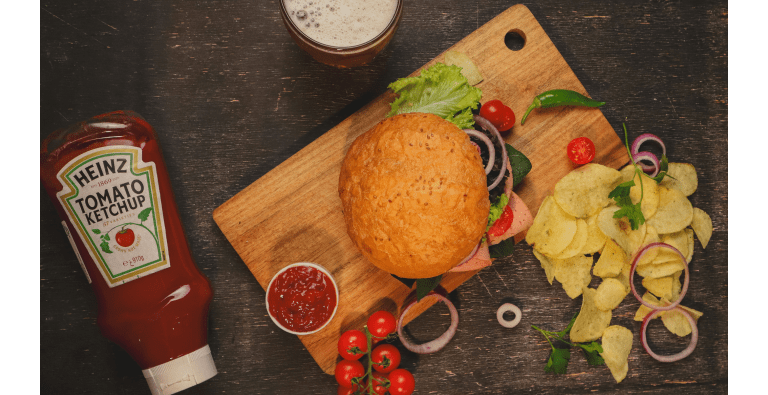 Burger with chips, ketchup, and beer.
