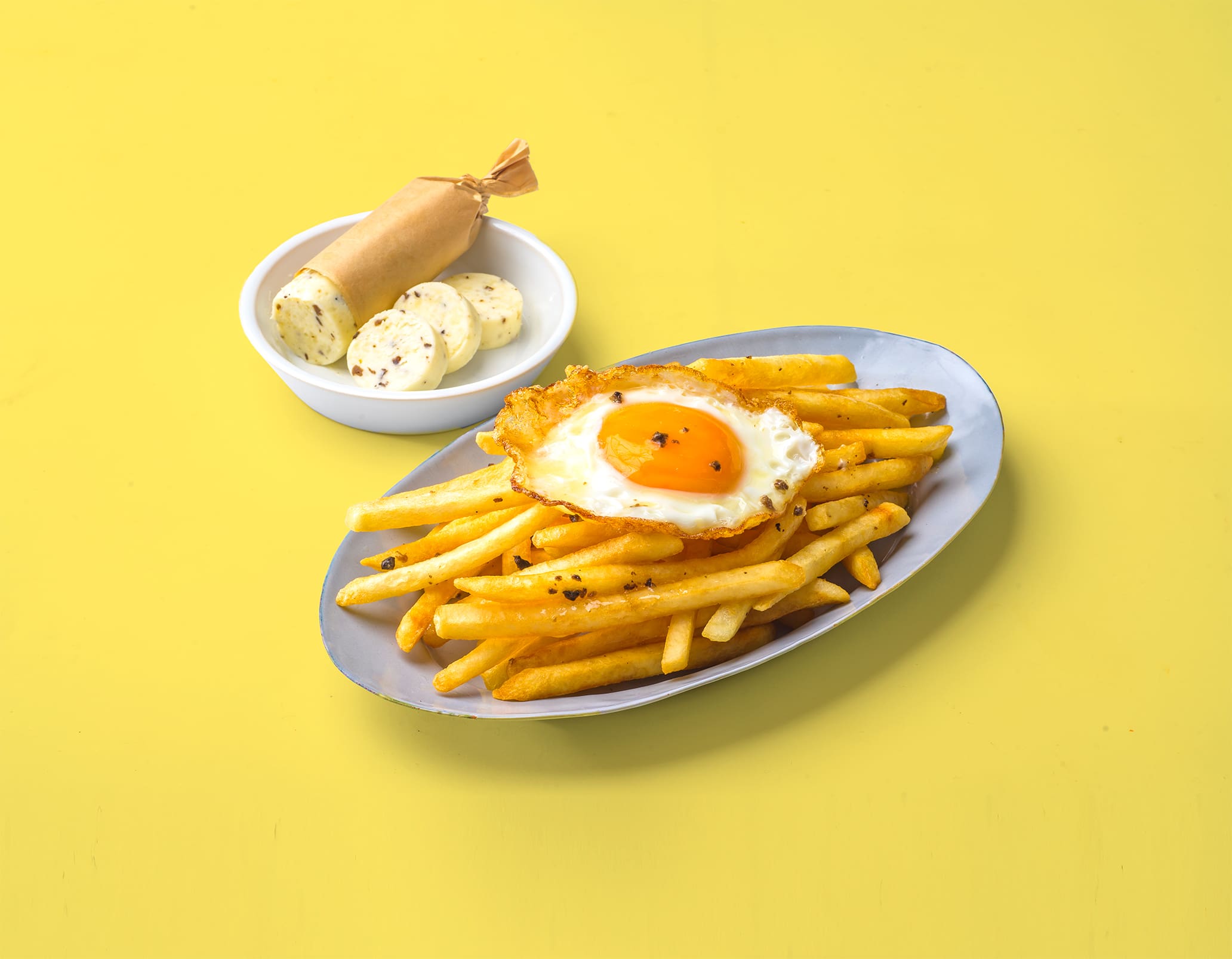 目玉焼きをのせたフライドポテトに、カットしたハーブ入りトリュフバターを添えて。