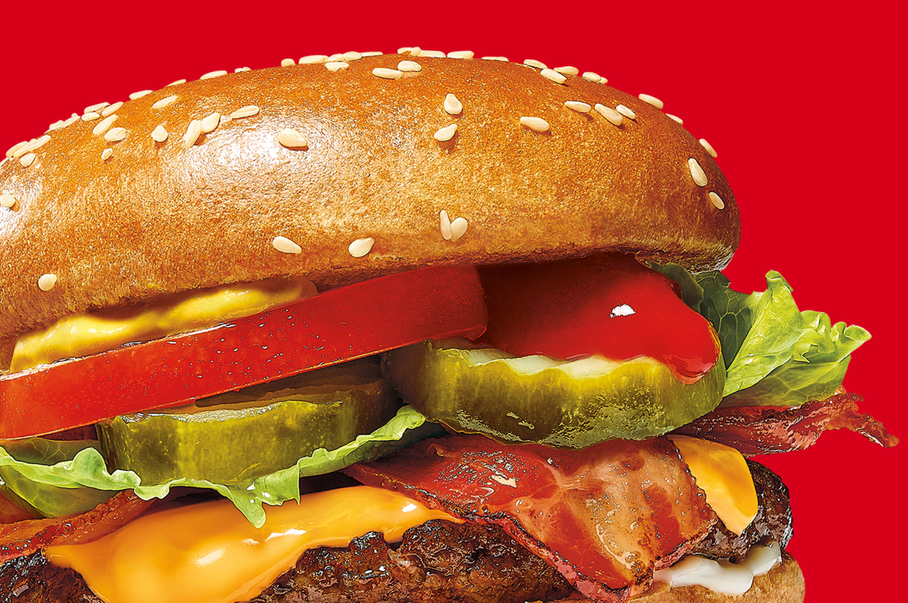 Delicious burger with bacon, cheese, veggies, and sesame bun.