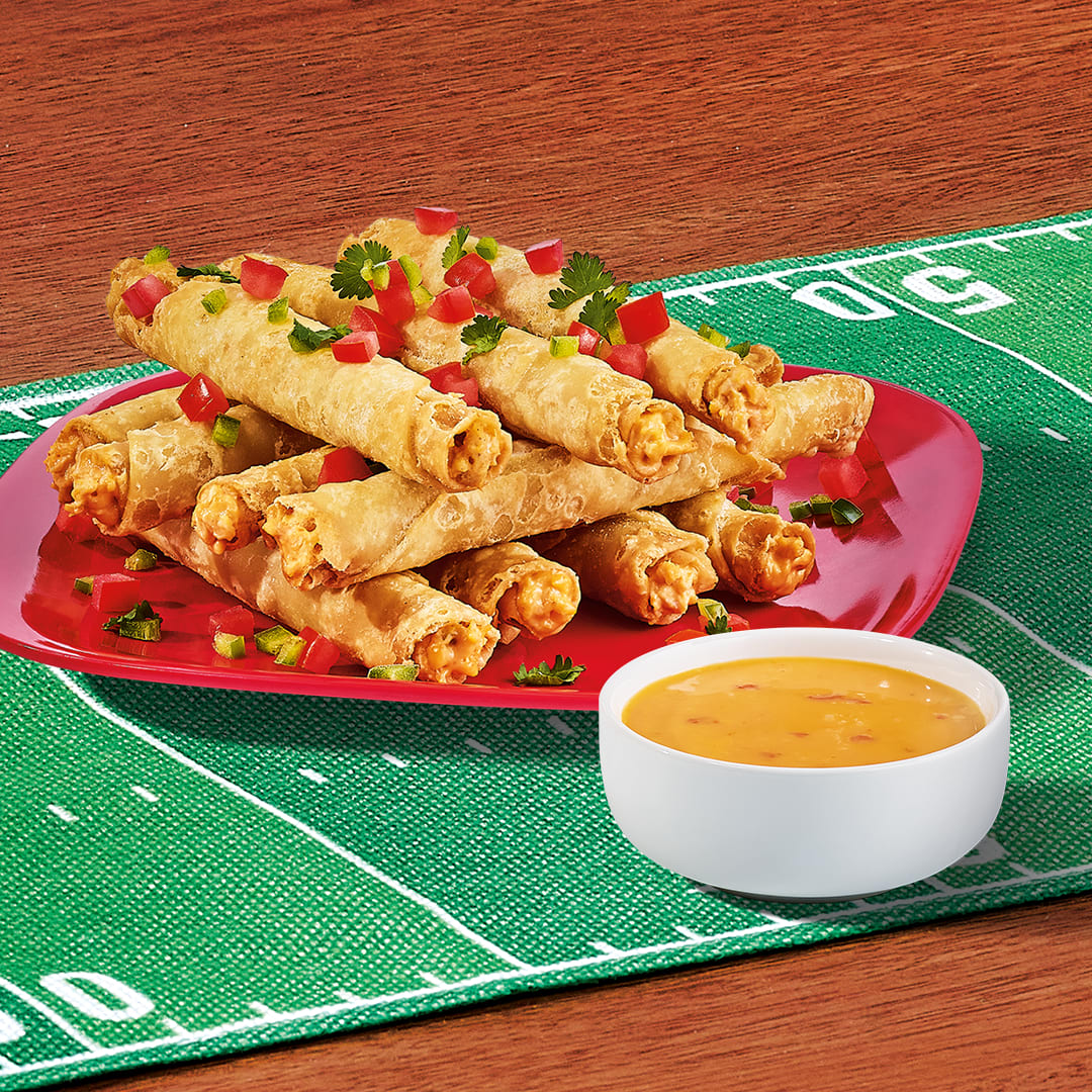 Crispy Delimex taquitos with a side of queso, garnished, a touchdown for your taste buds.