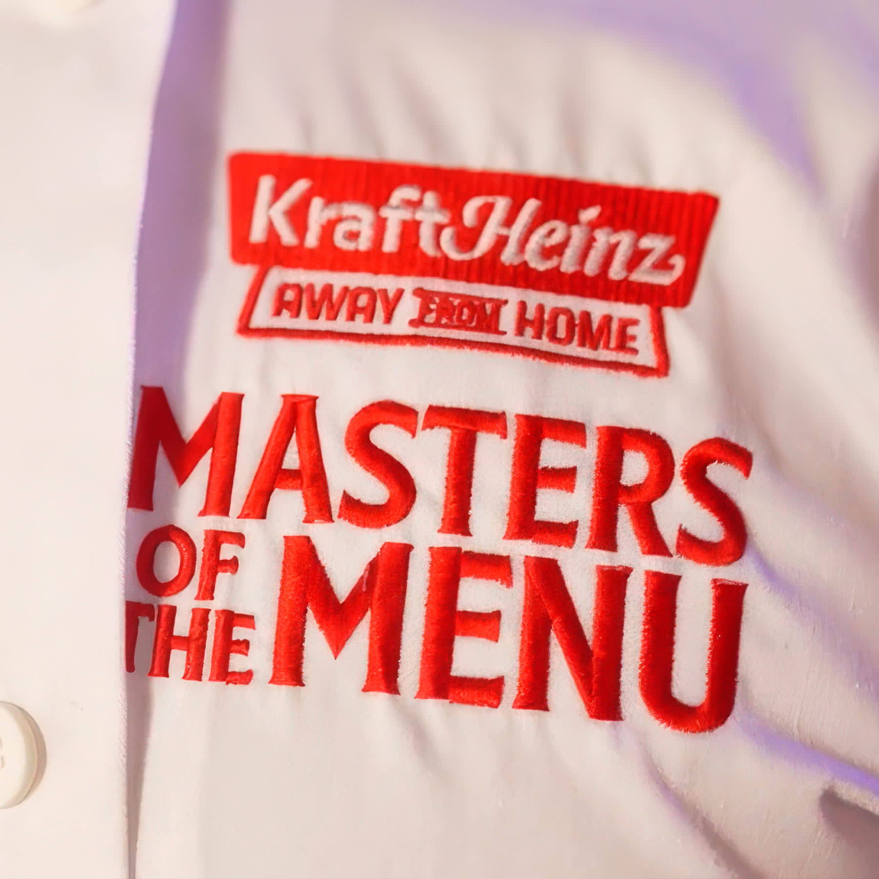 Chef James Cochran smiling and clapping at a Masters of the Menu event in a room with vibrant red lighting.