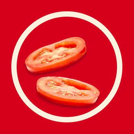 Two thin slices of ripe red tomato are presented on a vibrant red background, framed by a contrasting off-white circle. The juicy interior and seeds of the tomatoes are clearly visible. This image represents two servings.