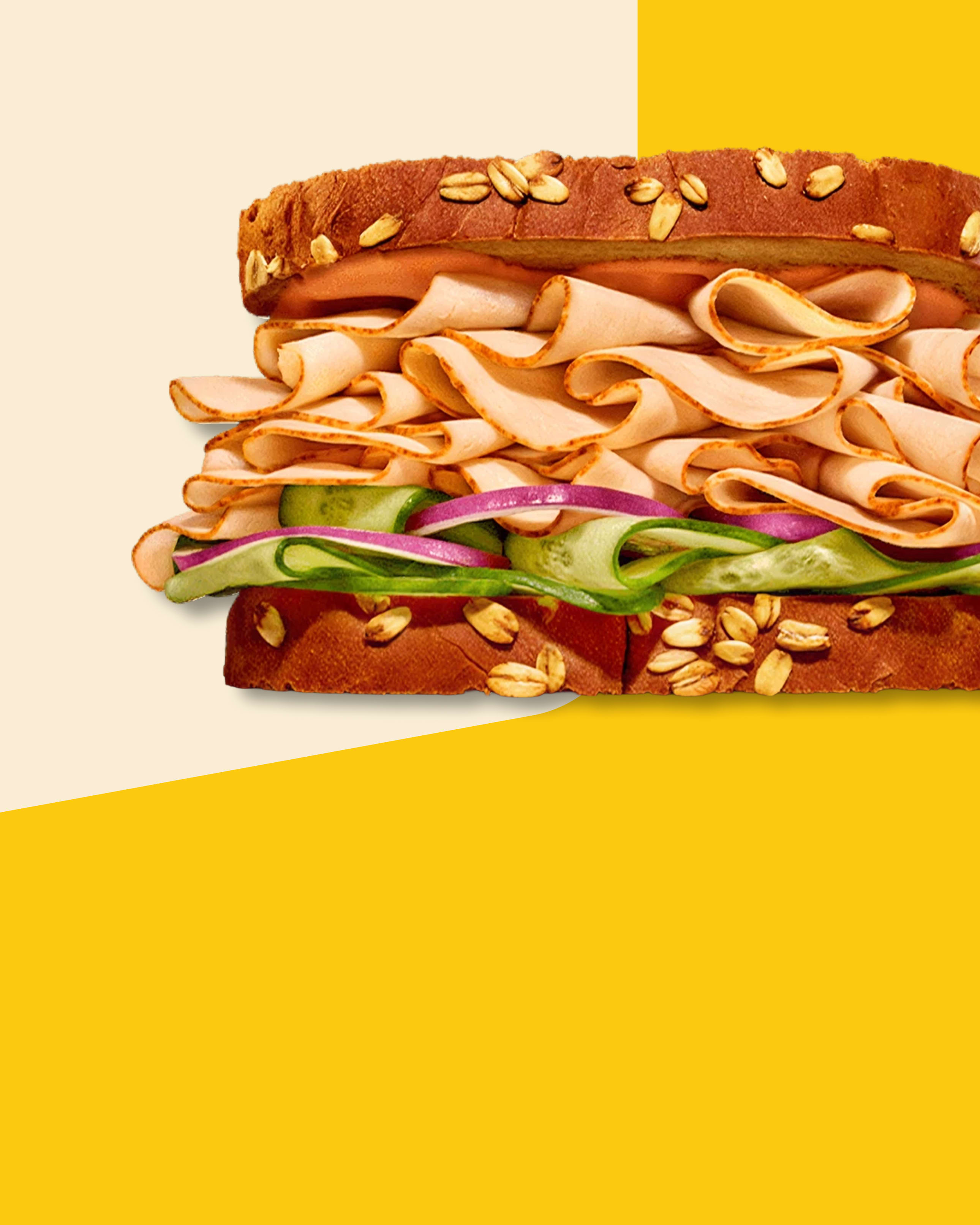 Oscar Mayer Deli Fresh turkey sandwich with cucumber and onion on oat wheat bread, set against a cream and yellow background.
