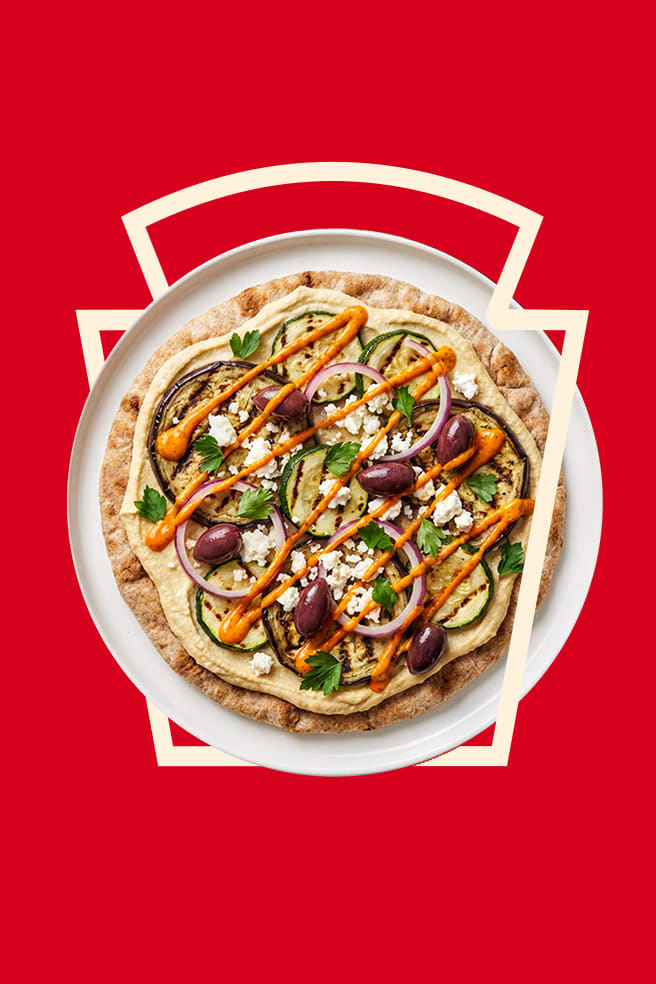 A Mediterranean flatbread with grilled veggies and Heinz Harissa Aioli, framed by the Heinz keystone.