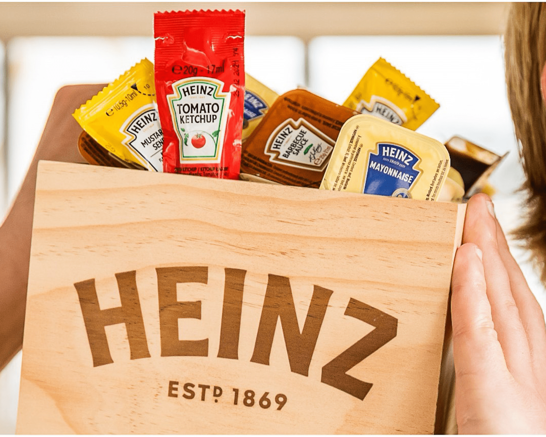 Een houten Heinz-doos gevuld met diverse condimentenpakjes.