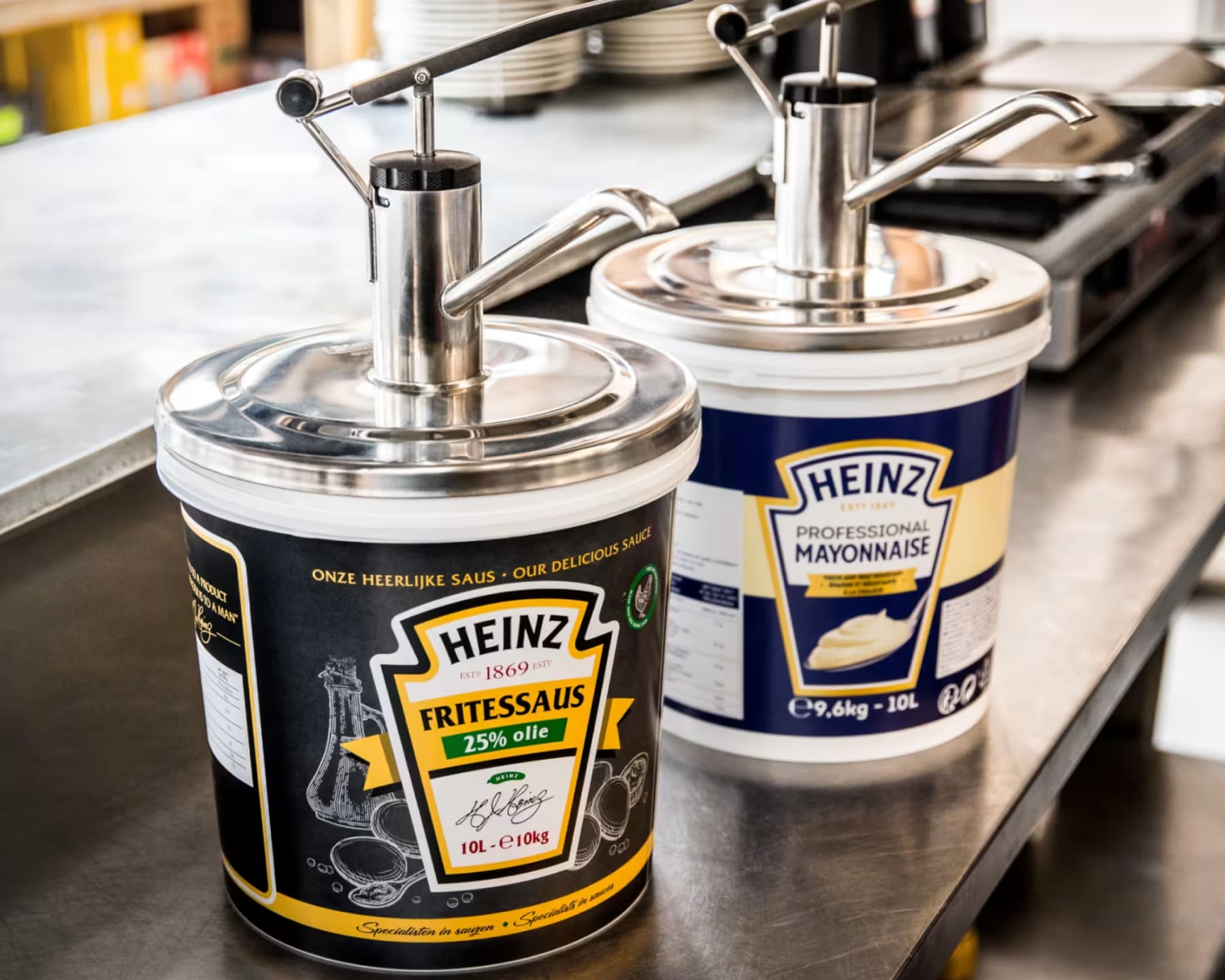 Grote containers met mayonaise en sauzen met dispensers op een aanrecht.