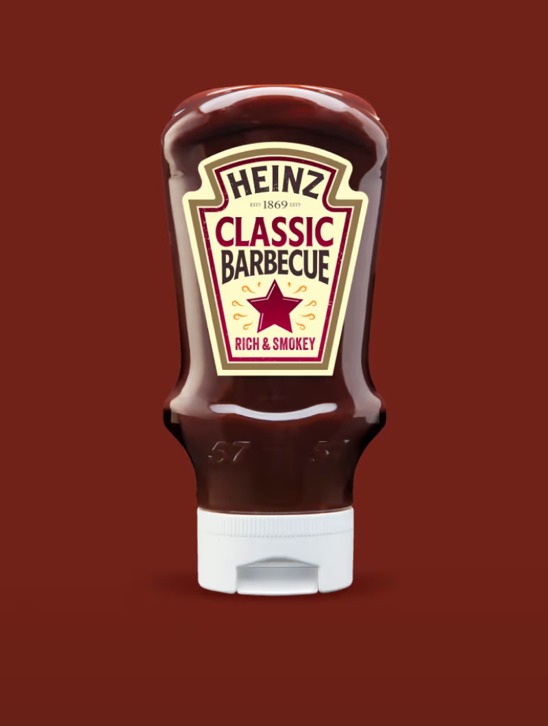 Hnědá láhev Heinz Classic Barbecue omáčky s bílou etiketou a grilem na hnědočerveném pozadí.
