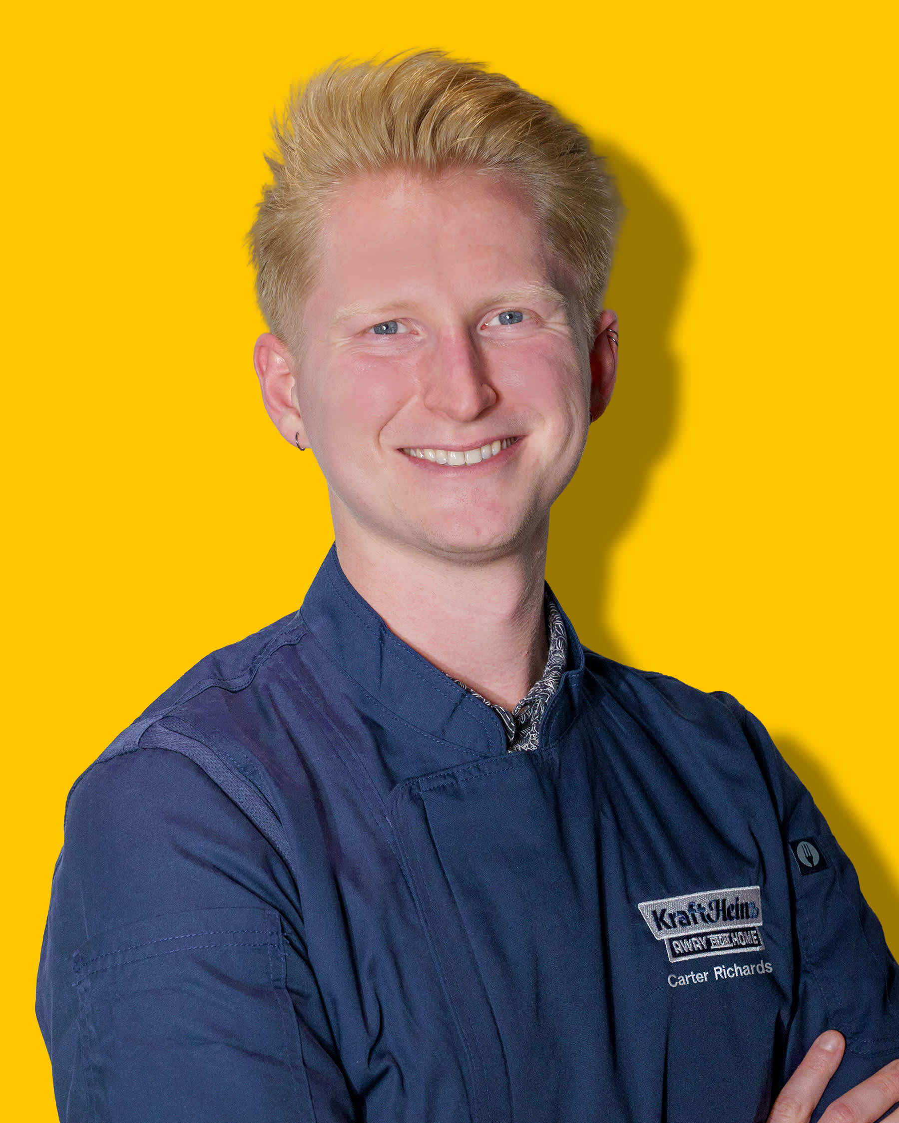 Headshot of Chef Carter Richards in navy uniform with yellow background.