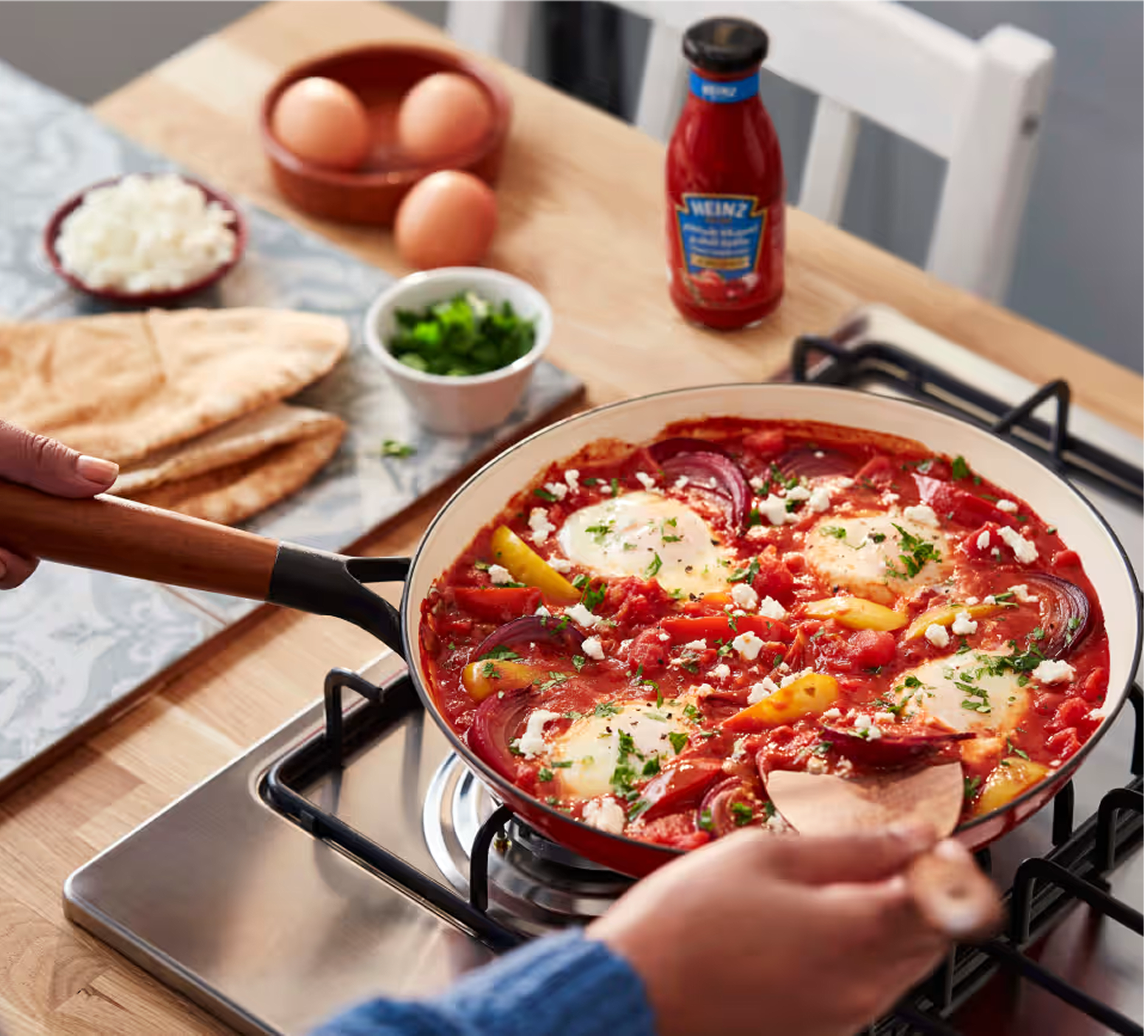 Shakshuka med pitabrød, æg, grøntsager og tomatsauce.