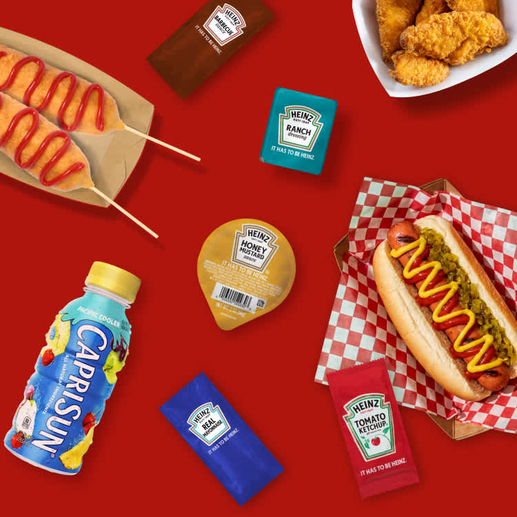 Convenience store grab-and-go food items including hot dogs, chicken, Capri Sun, and Heinz condiment packets.