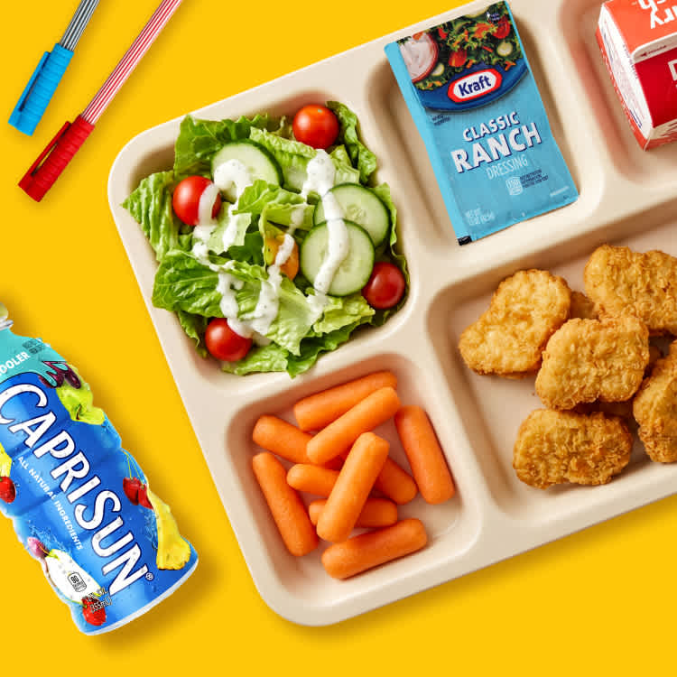 School lunch tray with salad, chicken nuggets, carrots, Kraft Classic Ranch, and Heinz Honey Mustard.