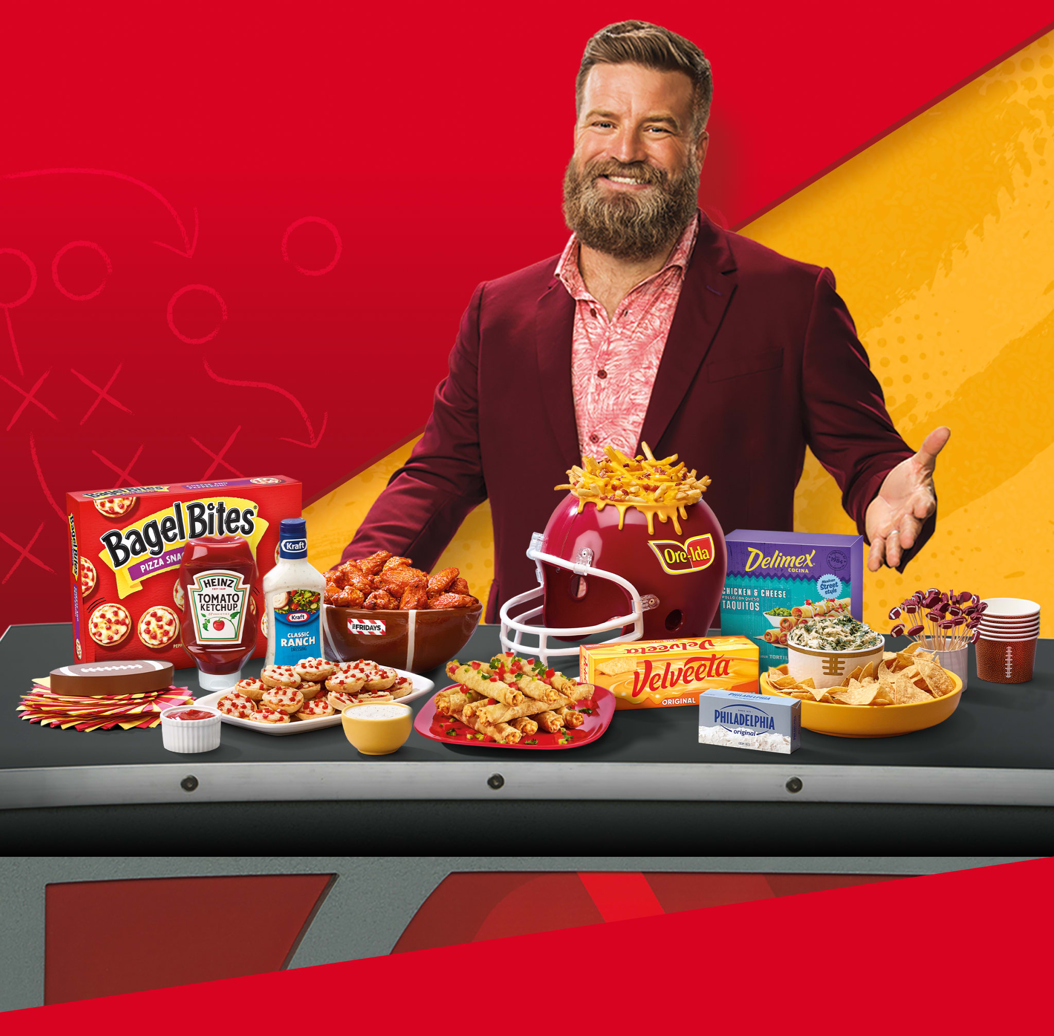 Man with beard, football helmet of Ore-Ida fries, and a spread of Kraft Heinz snacks: Bagel Bites, Heinz, Velveeta.