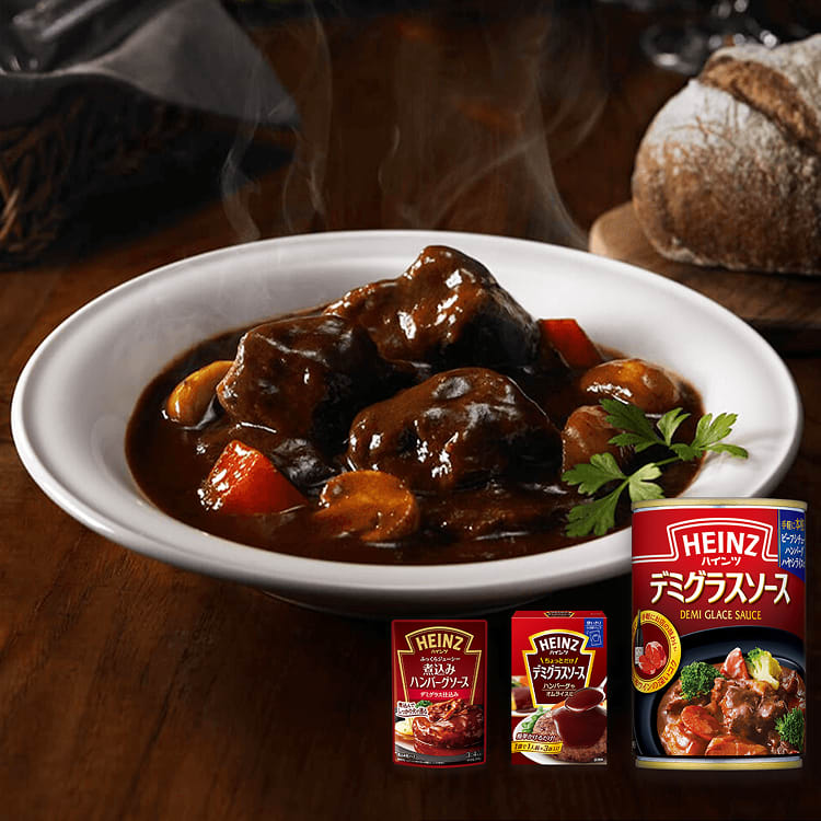 湯気が立ち上る濃厚なビーフシチュー（またはデミグラスソースを使った料理）のボウル。手前には3種類のハインツのデミグラスソース製品が置かれ、奥にはパンが見える木製のテーブルの上の写真。