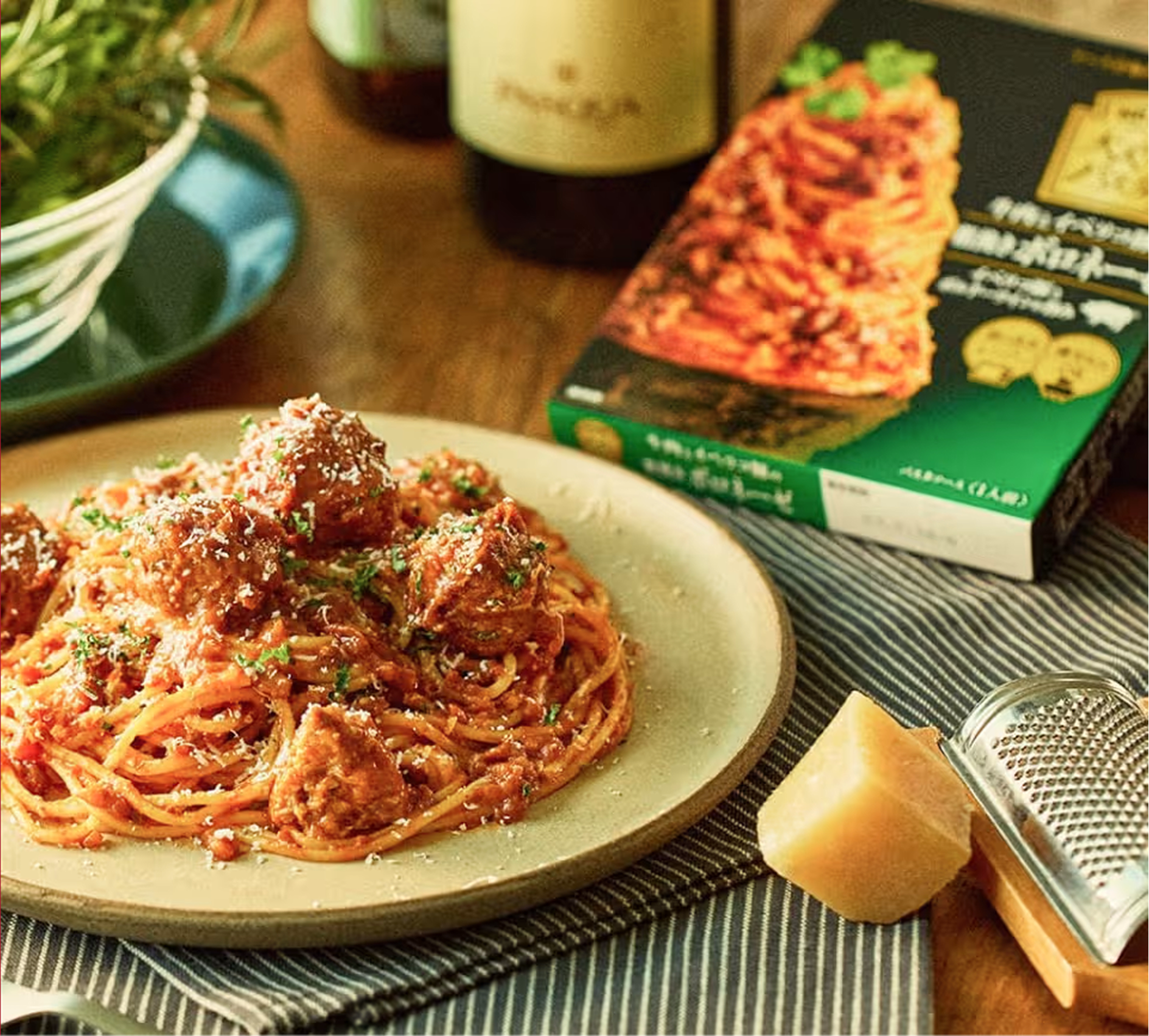 ミートボールスパゲッティ、粉チーズ、おろし器、ハインツのパスタソース箱。背景は木目調。