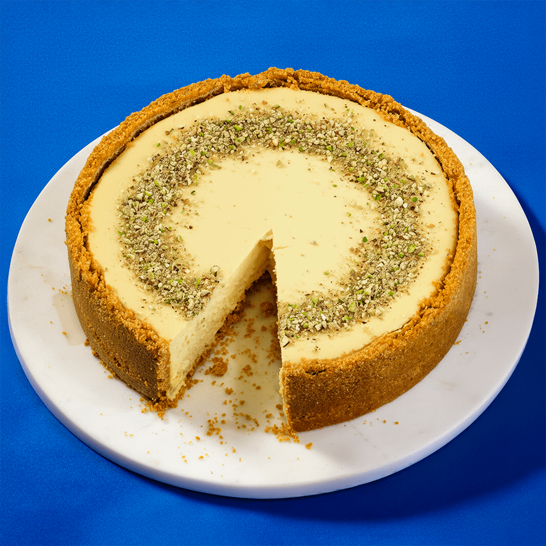 No Bake Pistachio Cheesecake made with Philadelphia Cream Cheese on a marble platter with a blue background.