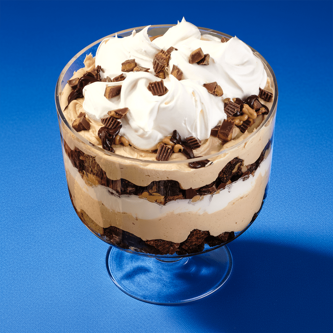 Layered Kraft Peanut Butter trifle with brownie, mousse, and whipped cream topped with peanut butter cups.