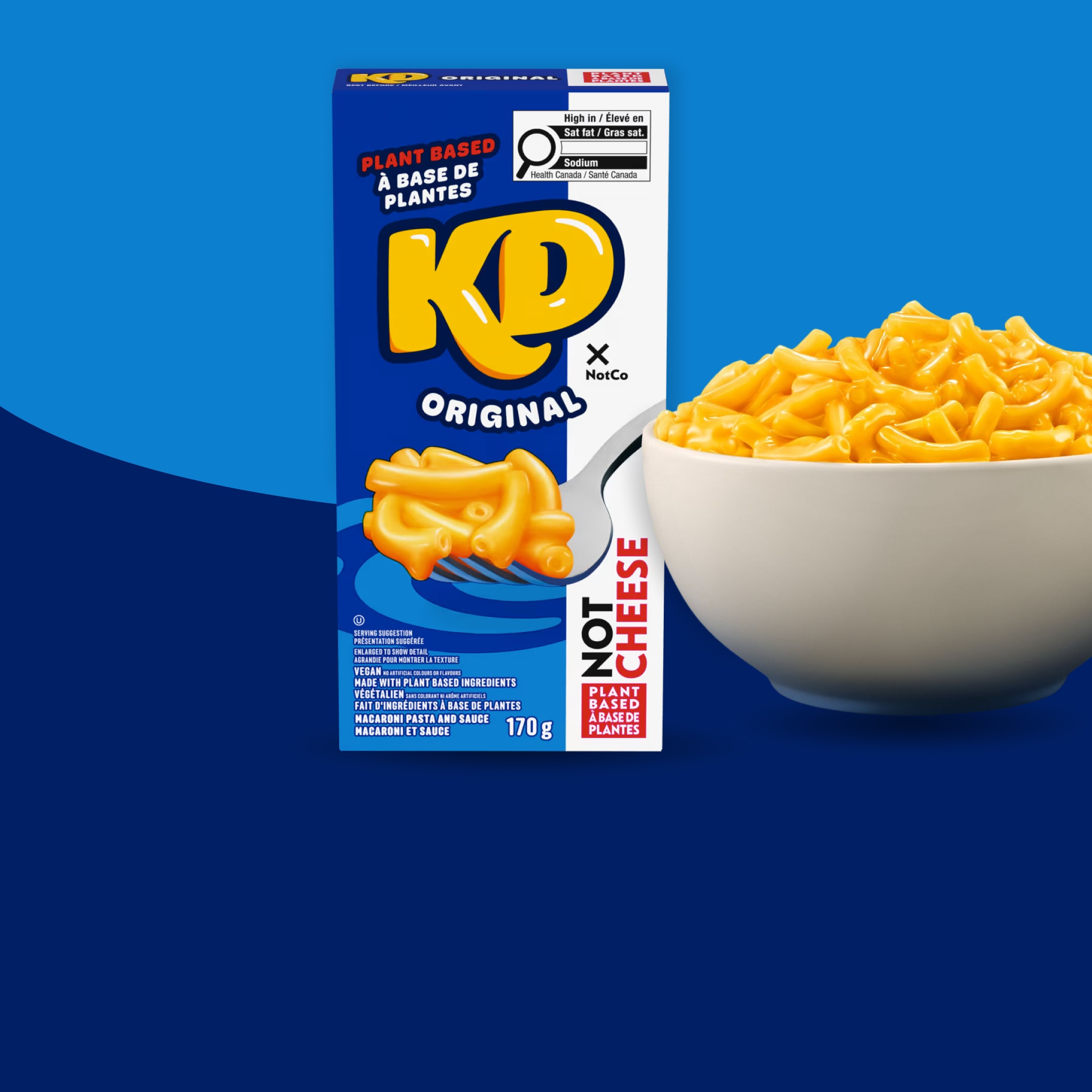 KD Original Plant-Based Mac and Cheese box next to a white bowl of cooked cheesy macaroni on a blue background.