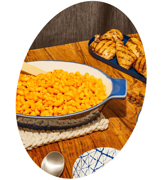 Mac and cheese and grilled chicken on a wooden table.