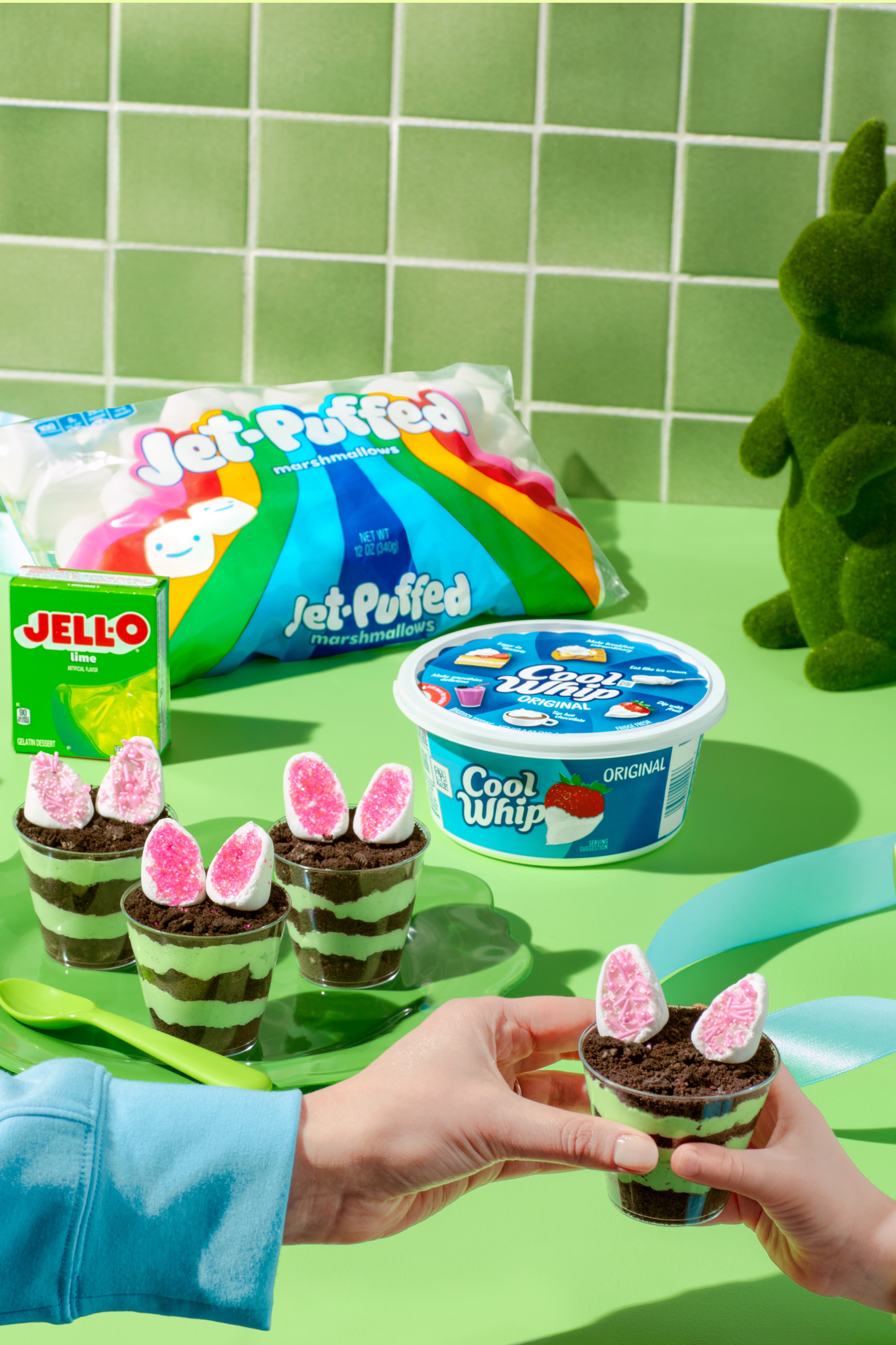 Easter dirt cups with green pudding, crushed cookies, and marshmallow ears next to Jet-Puffed and Cool Whip.