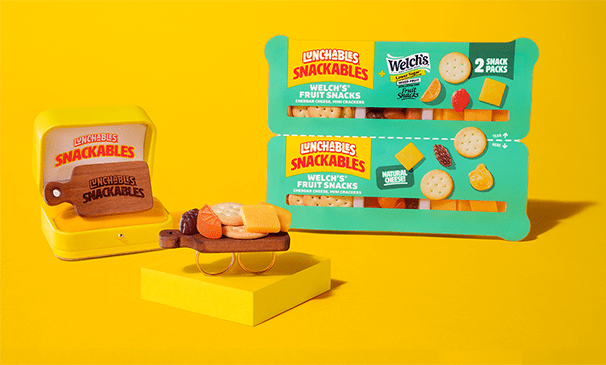 Lunchables Snackables Welch’s Fruit Snacks and cheese packs displayed with a mini charcuterie ring on a yellow background.