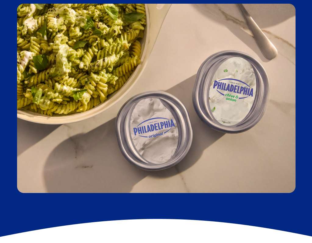 A photo of a pasta dish with two tubs of Philadelphia Cream Cheese