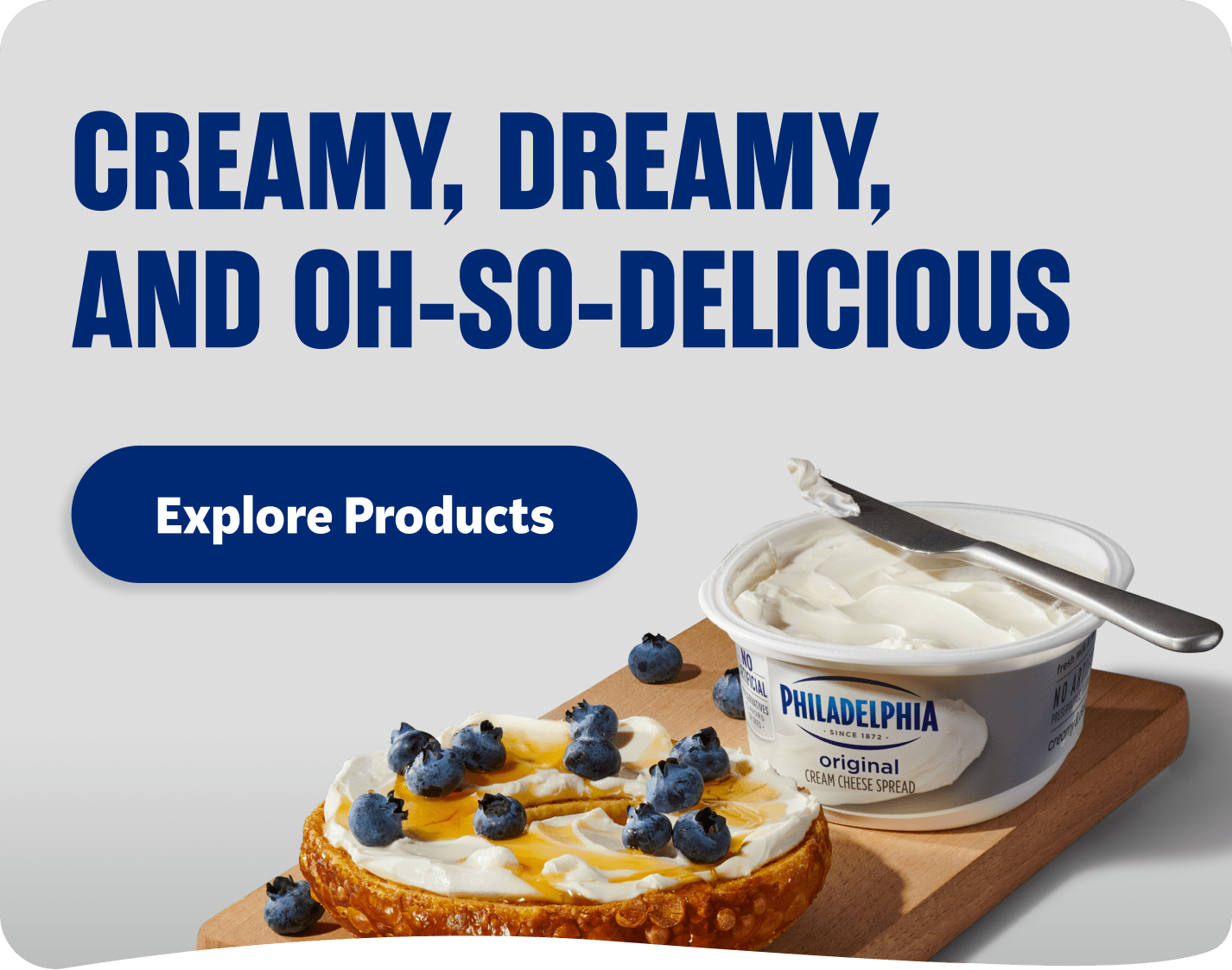 Philadelphia Cream Cheese spread on a bagel with blueberries and honey.