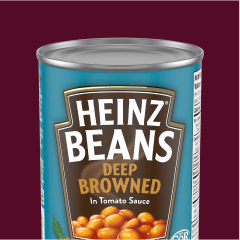 A can of Heinz Deep Browned Beans in Tomato Sauce, showing the label and some of the beans.