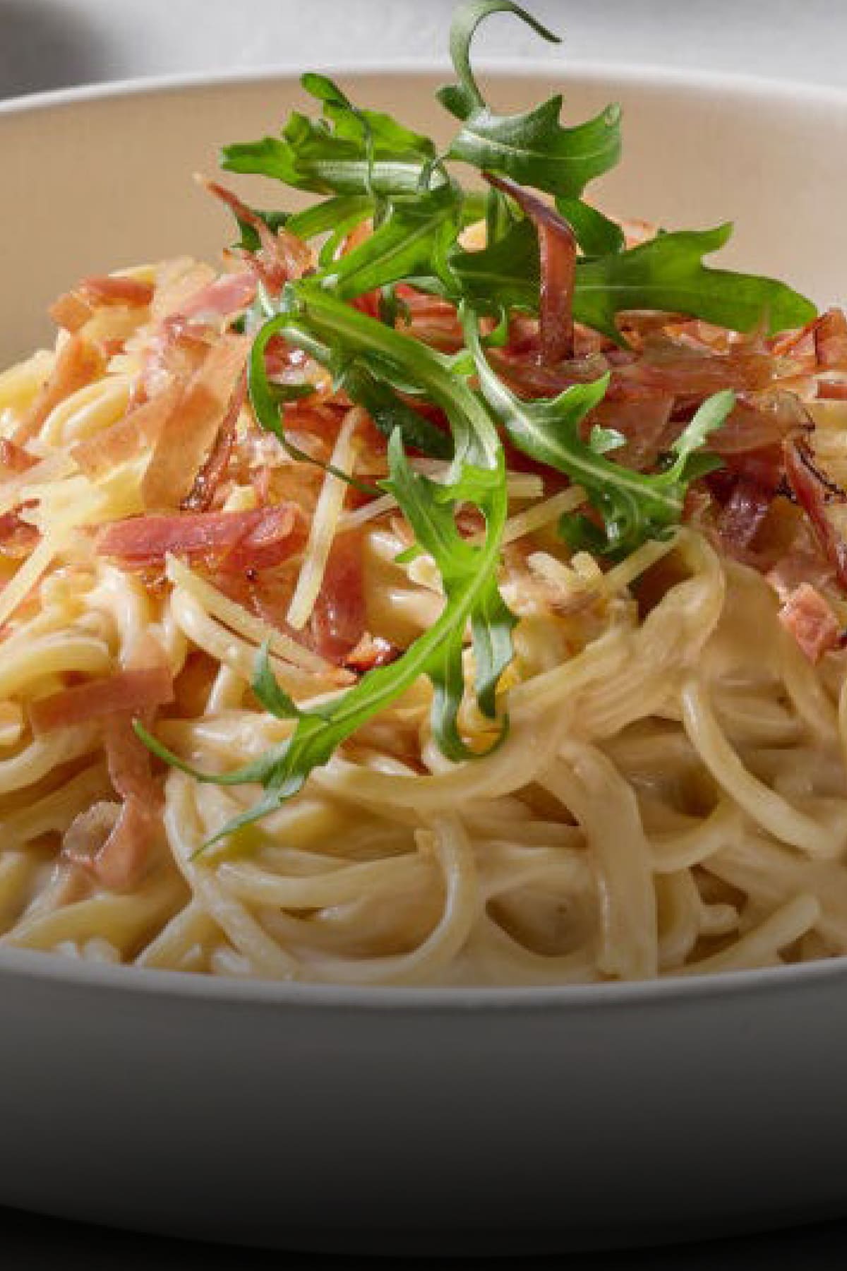 A close-up of spaghetti carbonara with creamy sauce made with PHILADELPHIA Cream Cheese, topped with crispy prosciutto and fr