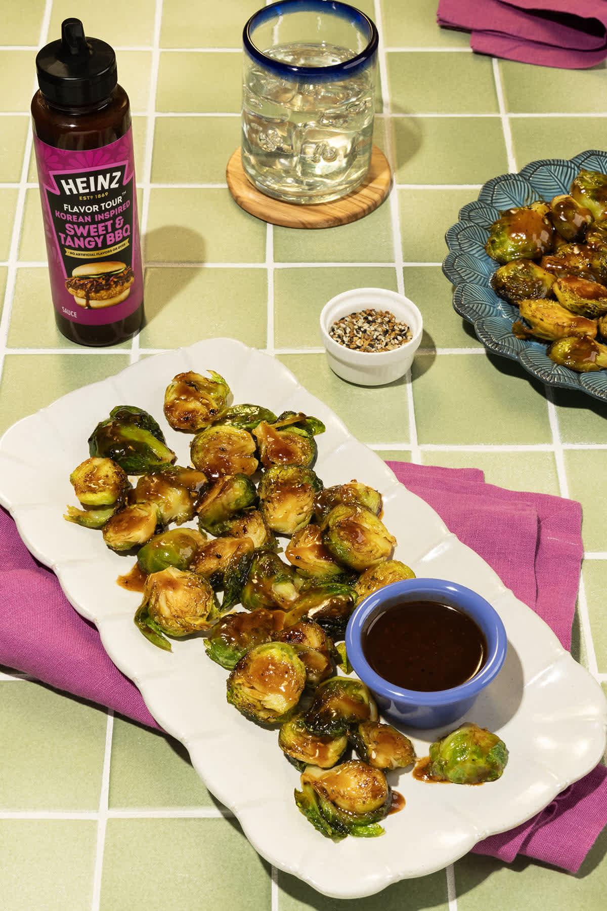 A close-up overhead image of a serving platter of smashed Brussels sprouts drizzled with Heinz Korean Inspired Sweet & Tangy 