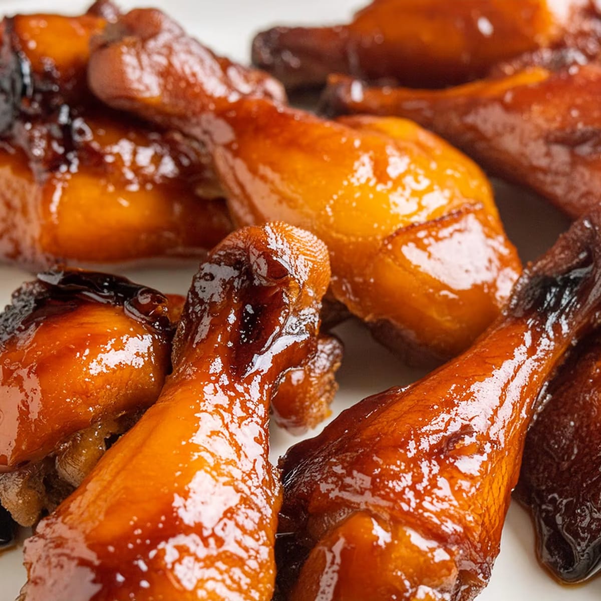 Close-up of glossy, honey-glazed roasted chicken drumsticks.