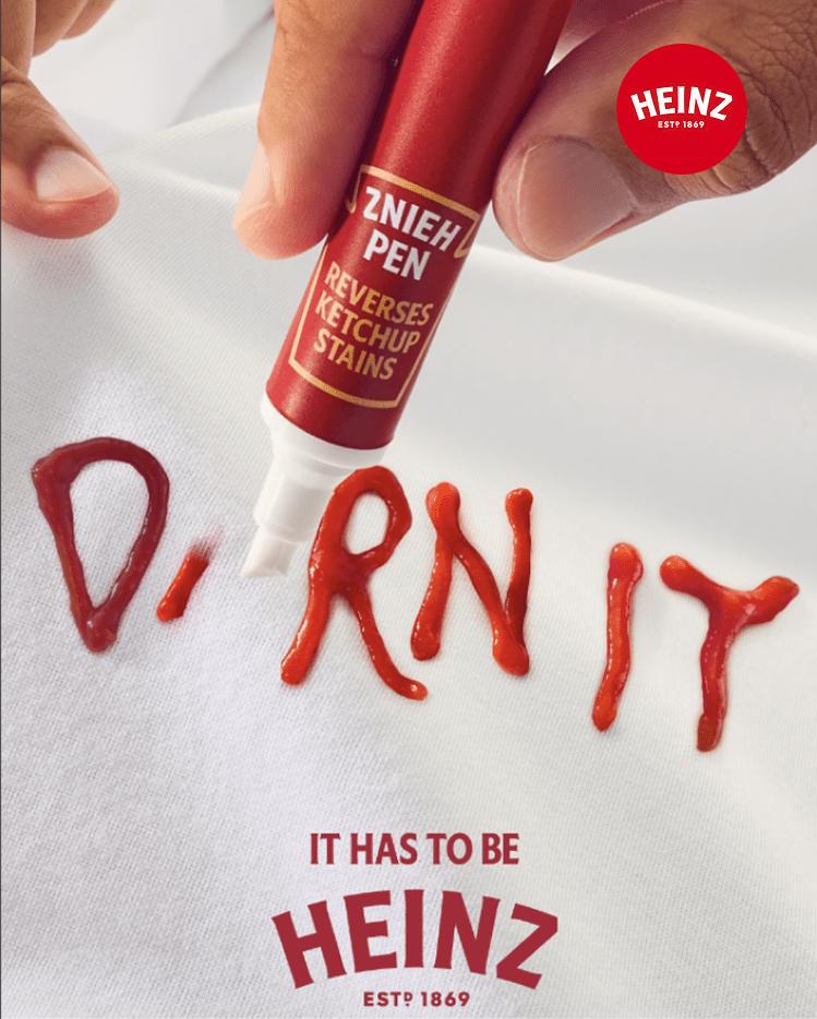 Hand using a Heinz "reverse ketchup" pen to clean a white shirt.