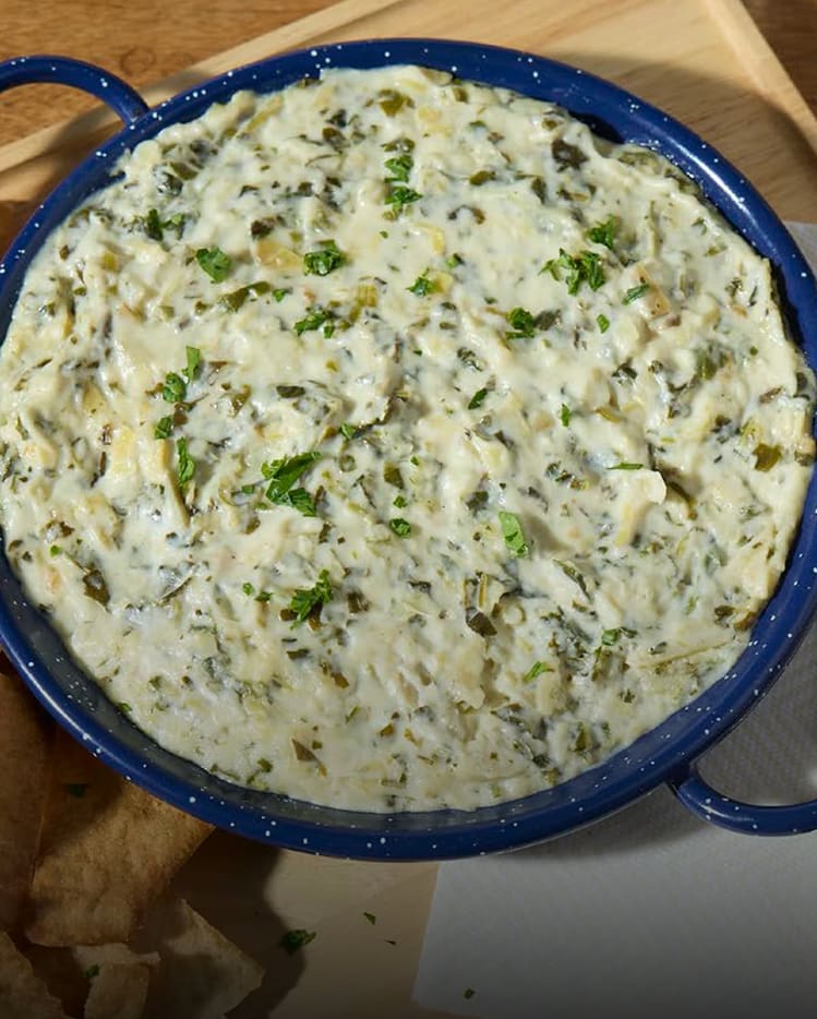 Creamy spinach artichoke dip made with Philadelphia cream cheese in a blue serving dish.