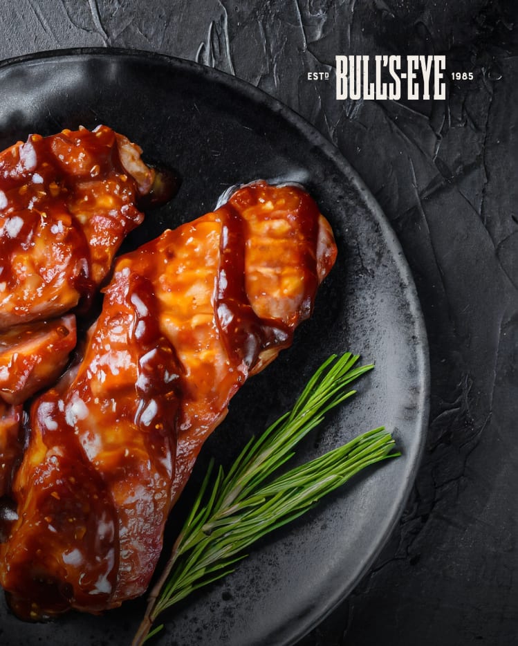 BBQ glazed pork ribs with rosemary on a black plate.