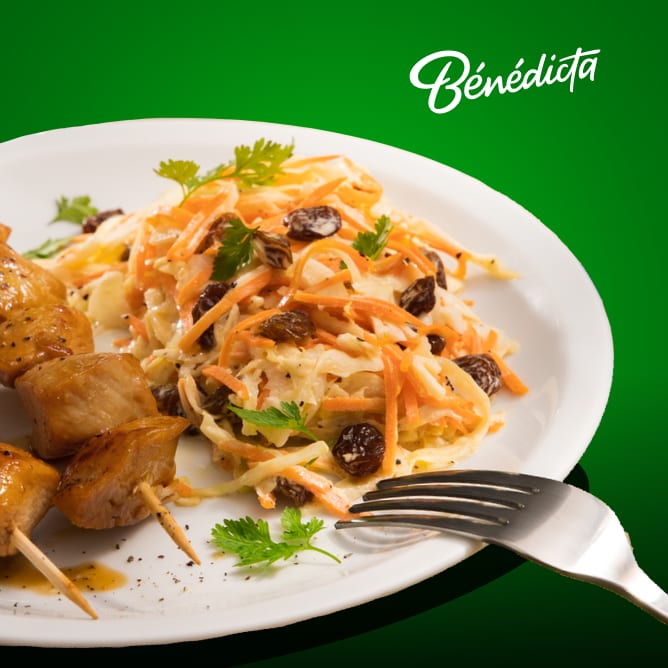 Chicken skewers served with a carrot and raisin salad under a Bénédicta logo.