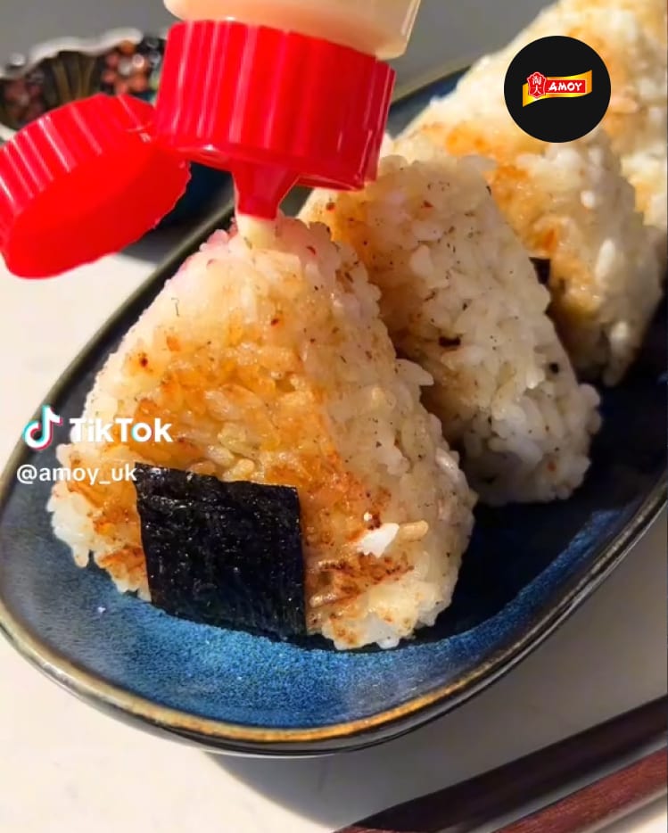 Three grilled onigiri rice balls being topped with sauce.
