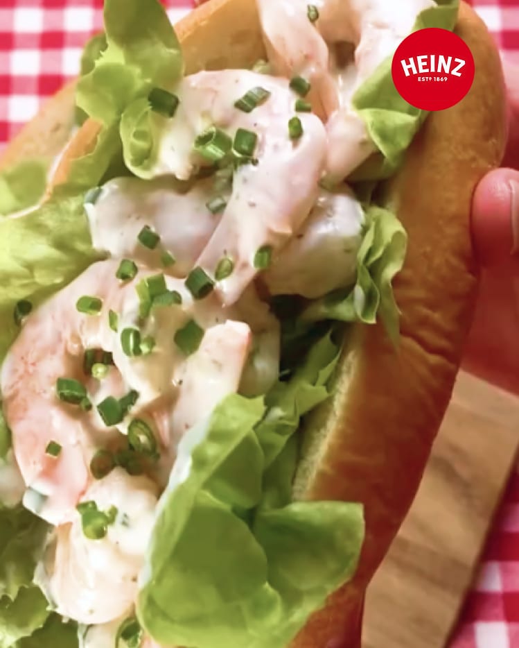 A shrimp roll with lettuce and chives on a red checkered background.