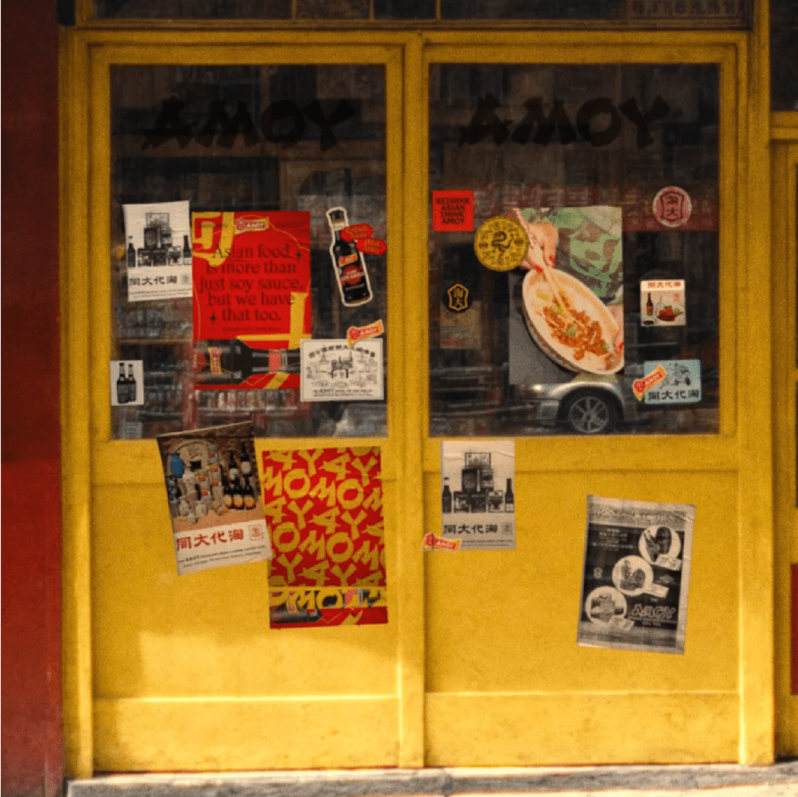 Shopfront covered in posters and signs for 'Amoy'.