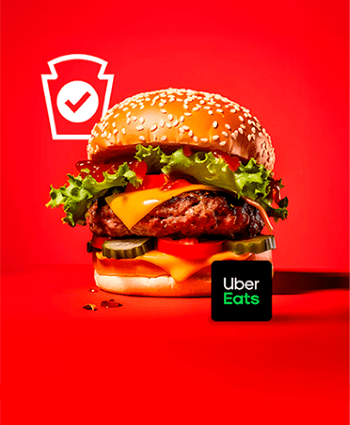 A juicy burger, complete with melted cheese, crisp lettuce, and ripe tomatoes, sits on a bold red background—a key color in t